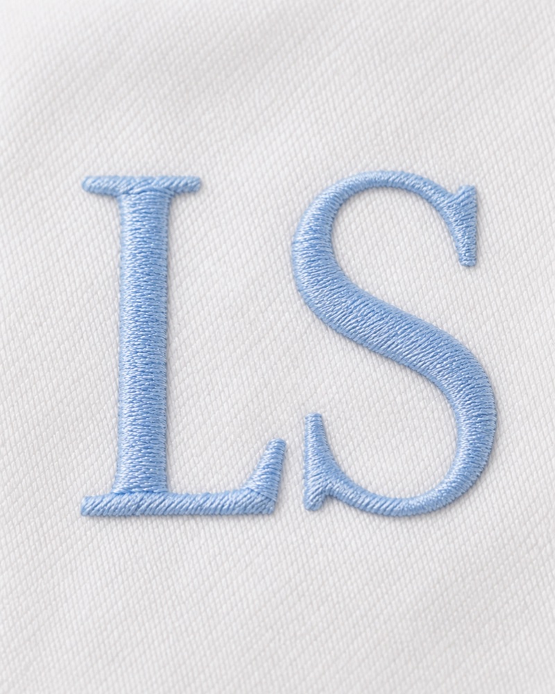 Close-up of machine-embroidered monogram on white linen